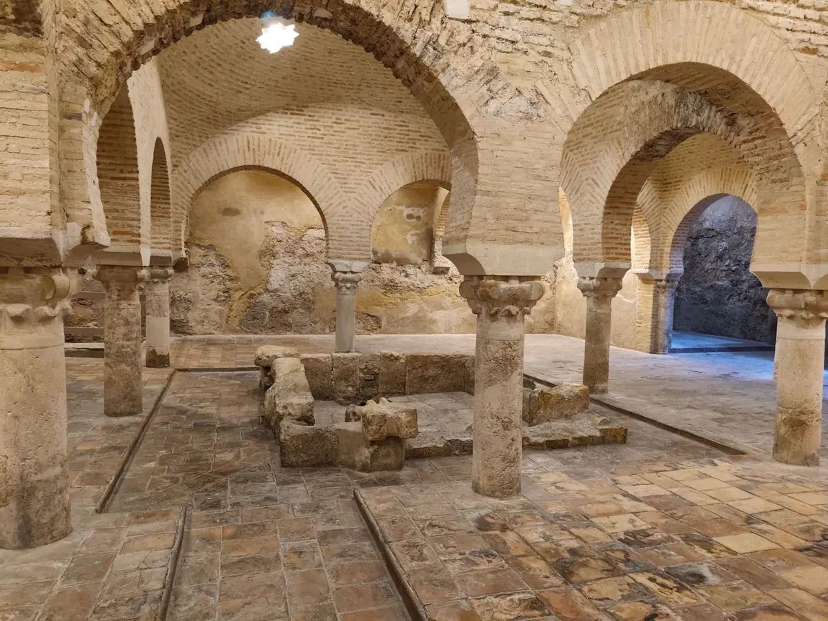 Baños árabes con arcos de herradura de ladrillo y columnas de piedra