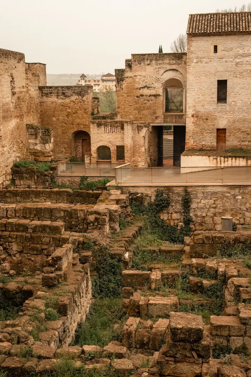 Muros de piedra excavados ante edificios históricos de ladrillo