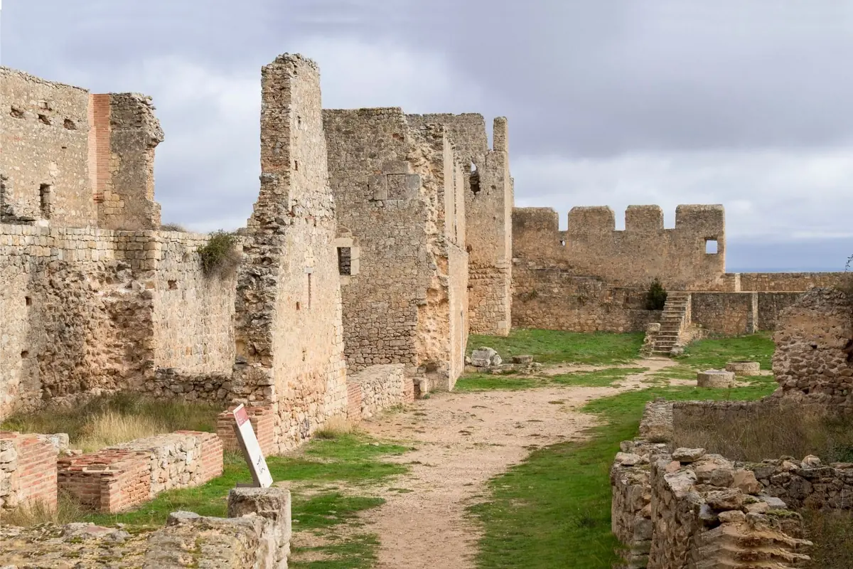 Recinto amurallado de un castillo en ruinas con un camino de tierra